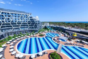 A modern hotel with a large pool area, multiple swimming pools, and a distinctive hexagonal building structure.