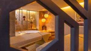 Un cuarto de spa con una bañera, una camilla de masaje y un estante con adornos.