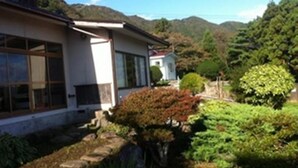 A house with a garden, a small pond, and a mountain in the background. - Hakodateyama Guest House - Hostel (Hakodate)