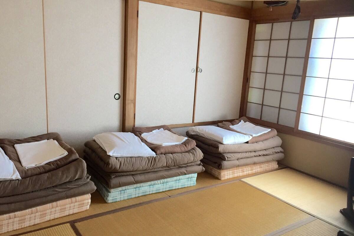 A traditional Japanese room with tatami flooring, a low table, and a futon bed arrangement.