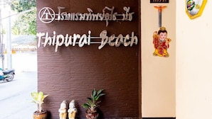 A sign for Thippurai Beach with Thai script and a small Buddha statue. - Thipurai Beach Hotel (Hua Hin)