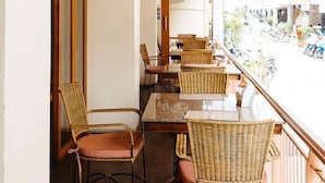 An indoor seating area with wicker chairs and tables, wooden ceiling beams, and wall-mounted lamps. - Thipurai Beach Hotel (Hua Hin)