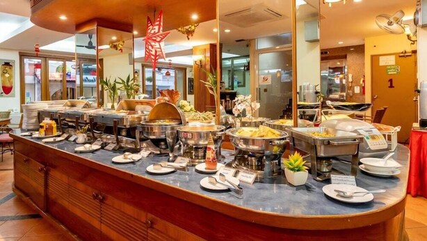 A buffet counter with various food stations, a mirror, and a decorative red star. - Thipurai Beach Hotel (Hua Hin)