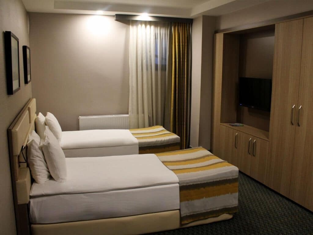 A hotel room with two beds, a wardrobe, and a television.