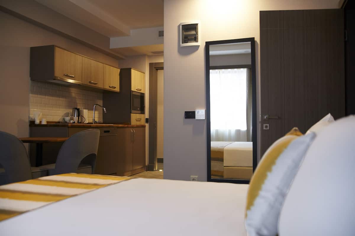 A hotel room with a bed, a desk, and a kitchenette.
