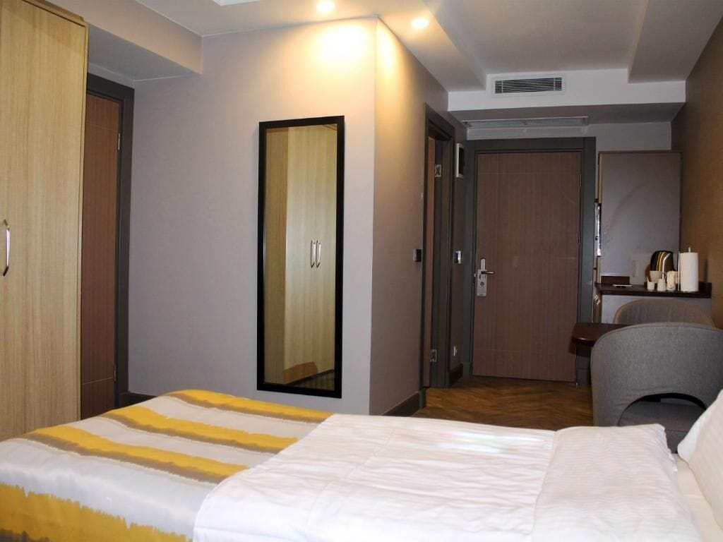 Une chambre d’hôtel comprenant un lit, une armoire, un miroir, un bureau et une chaise.