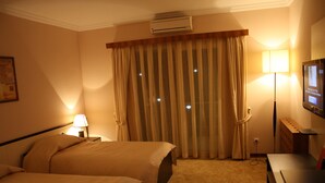 A hotel room with two beds, a flat-screen TV, an air conditioning unit, a lamp, and a desk. - Qafqaz Sahil Resort Hotel (Lankaran)