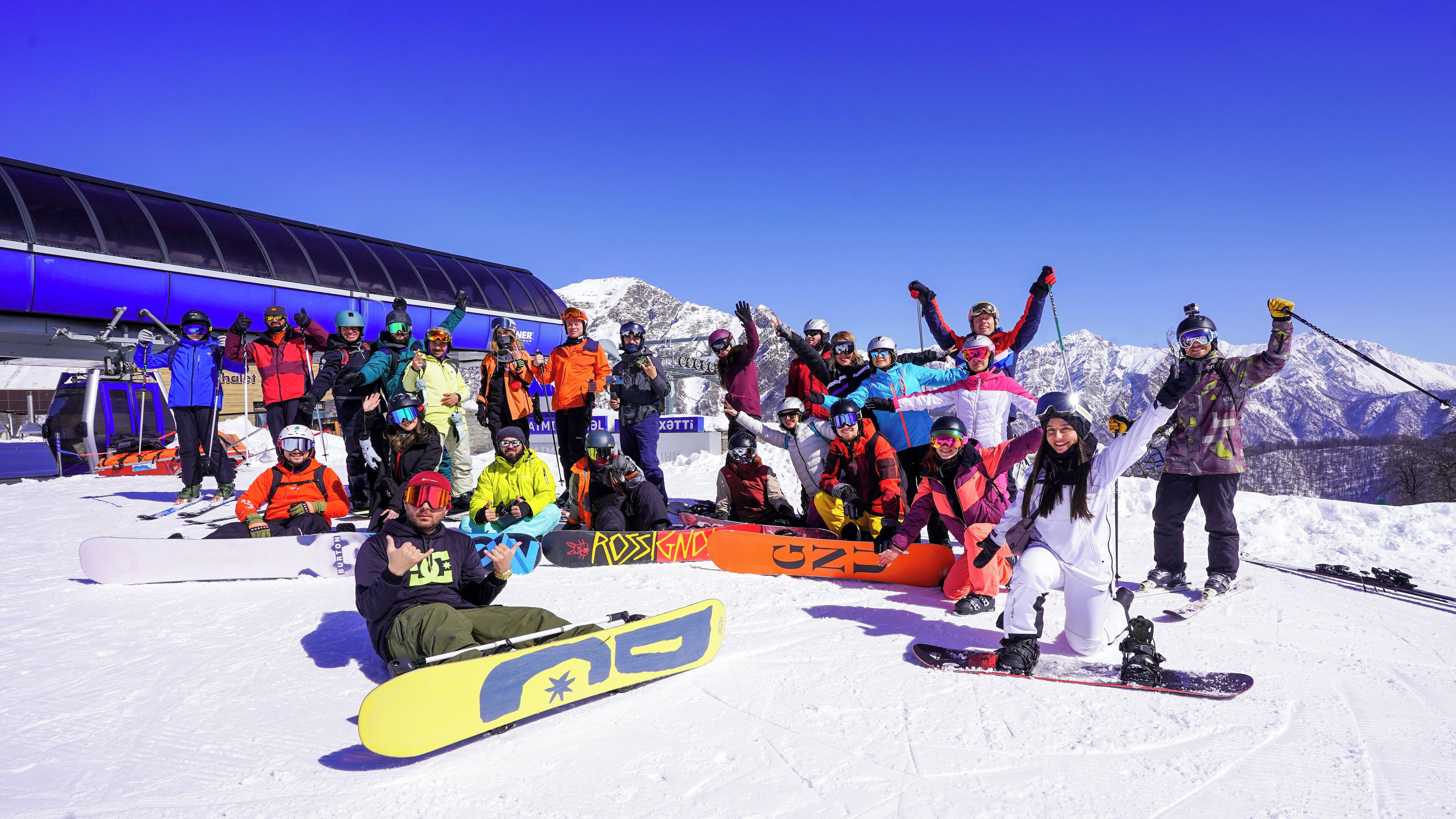 A group of people on a snowy slope with a ski lift in the background.