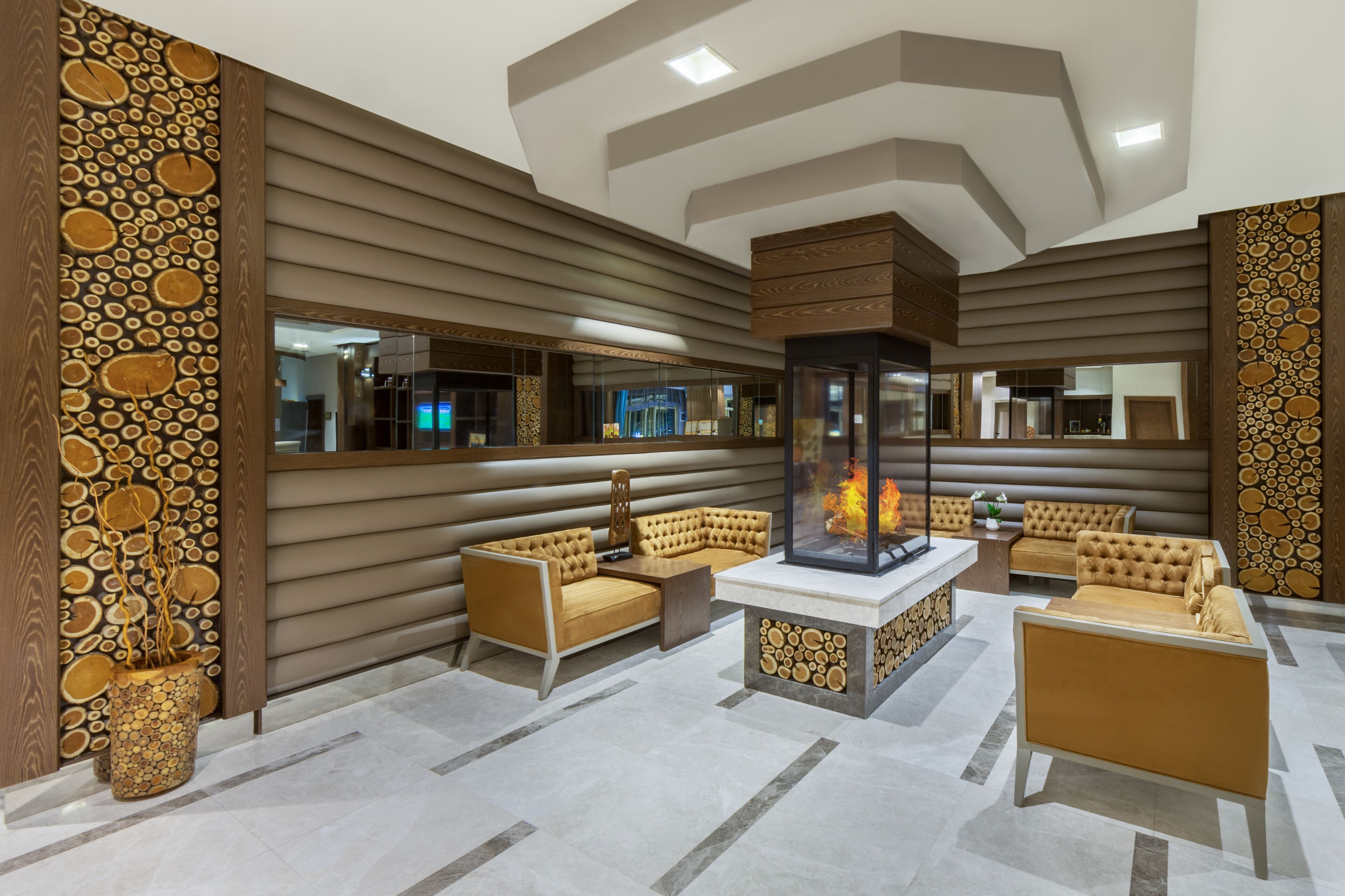A modern lounge area with a fireplace, leather sofas, and a decorative wall with circular patterns.