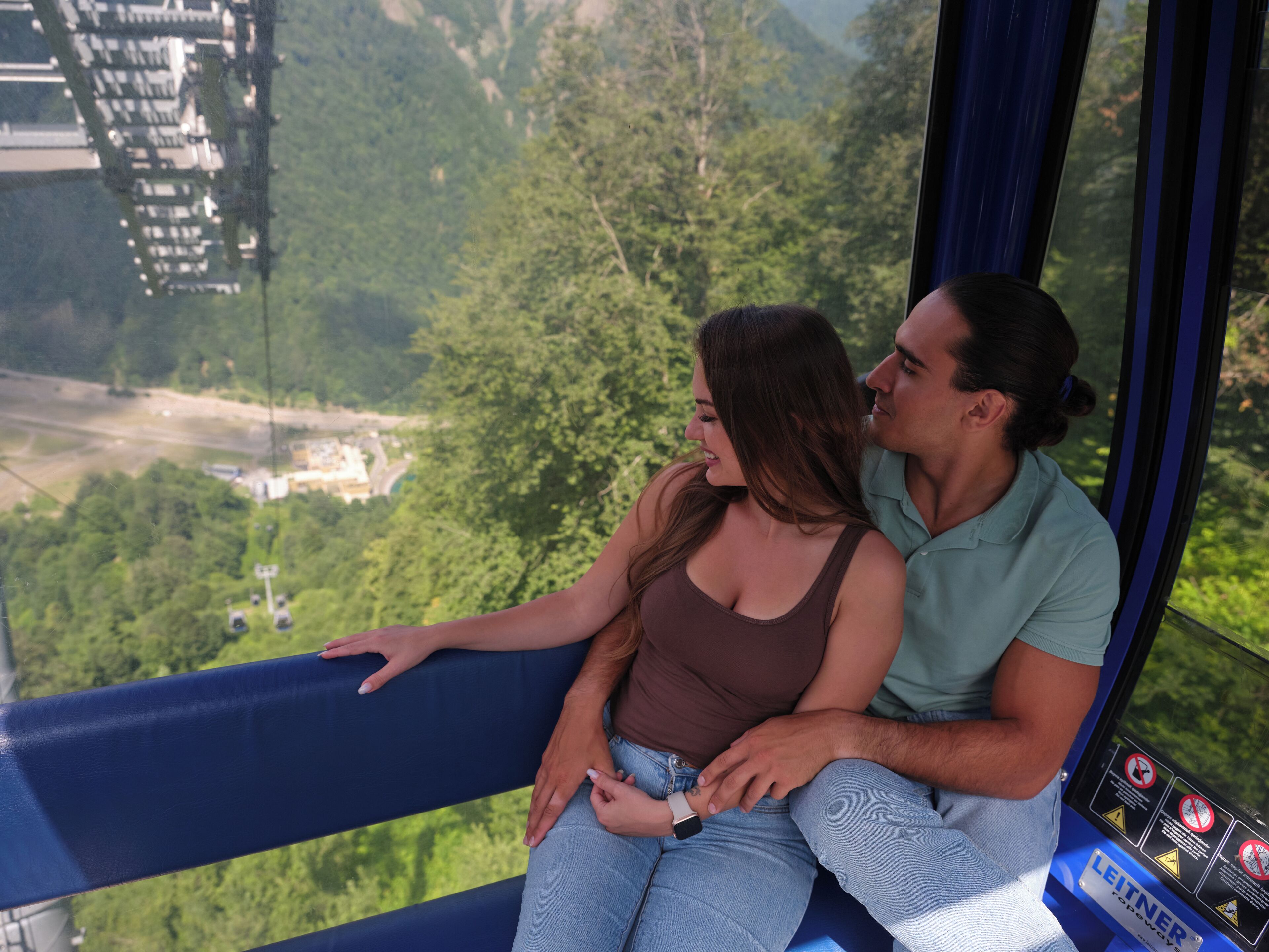 A couple sitting on a balcony with a view of a lush green landscape.