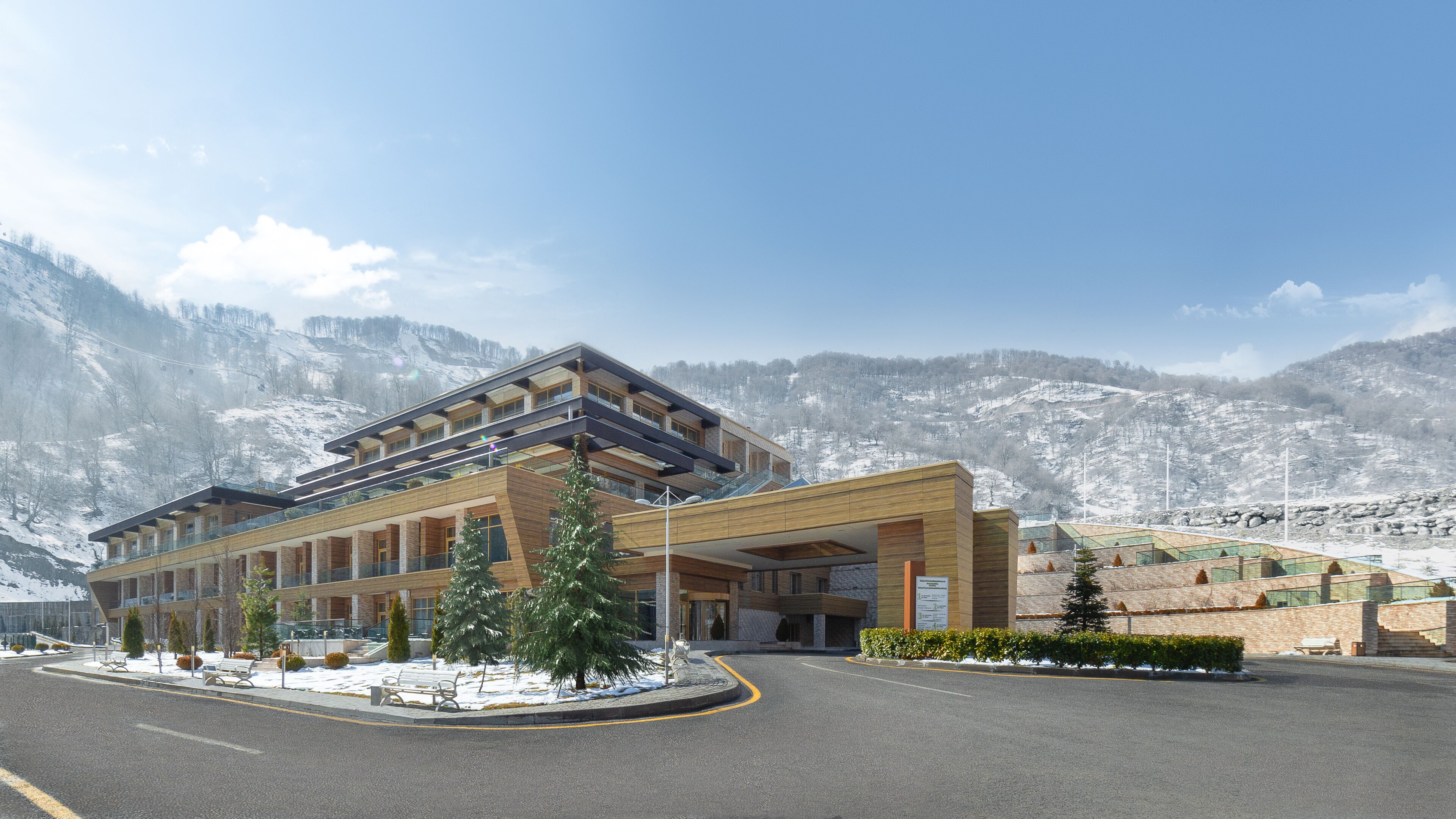 Un hotel modern amb una estructura de diversos pisos, seients exteriors i vistes a muntanyes cobertes de neu.