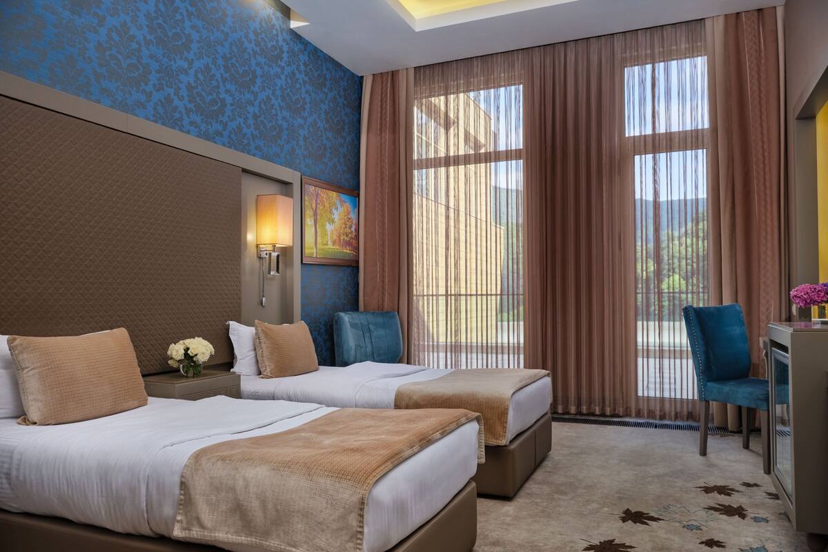 Habitació d'hotel amb dos llits, una taula i una cadira.