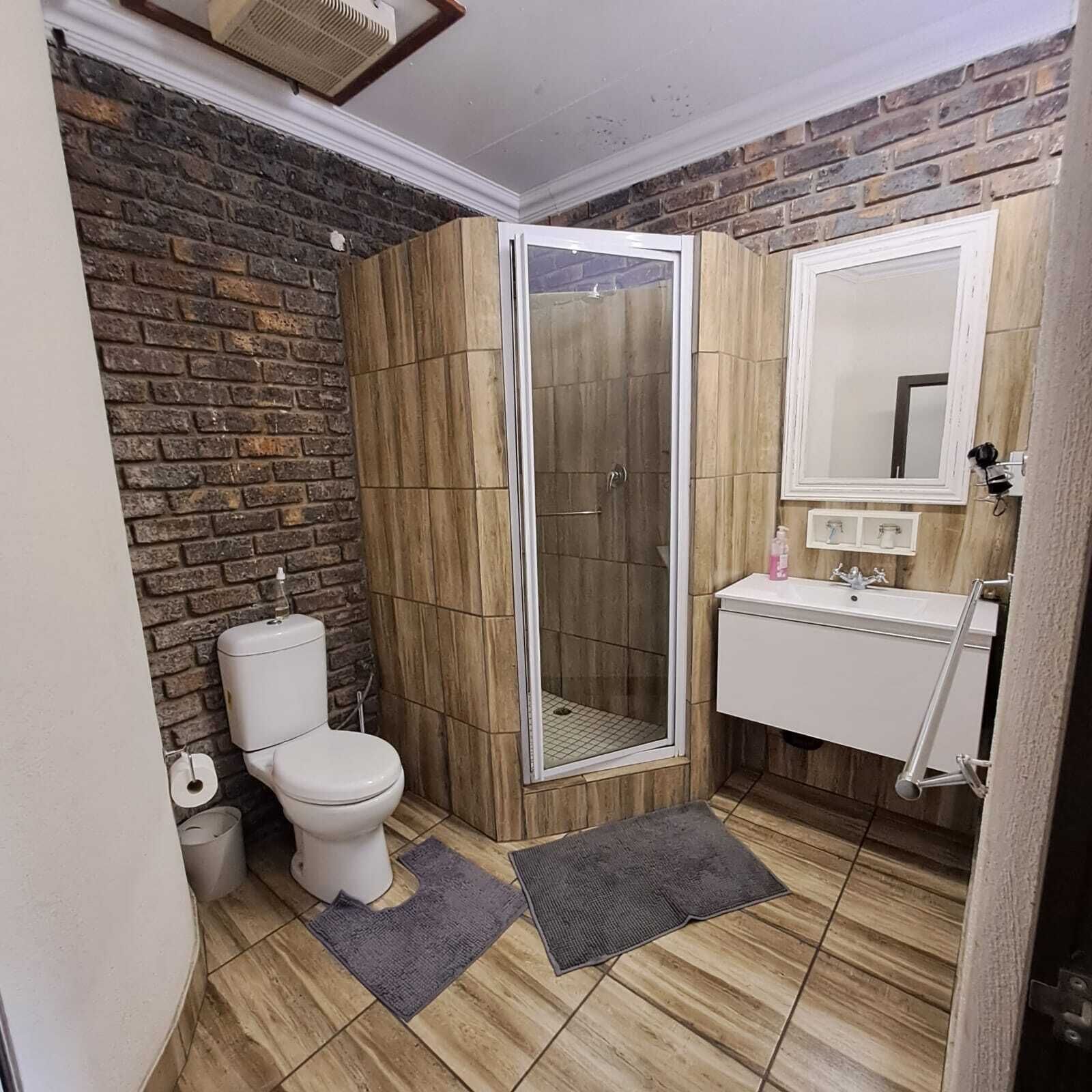 A bathroom with a shower, toilet, sink, and a mirror.