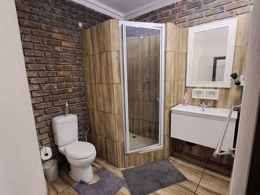 A bathroom with a shower, toilet, sink, and a mirror.