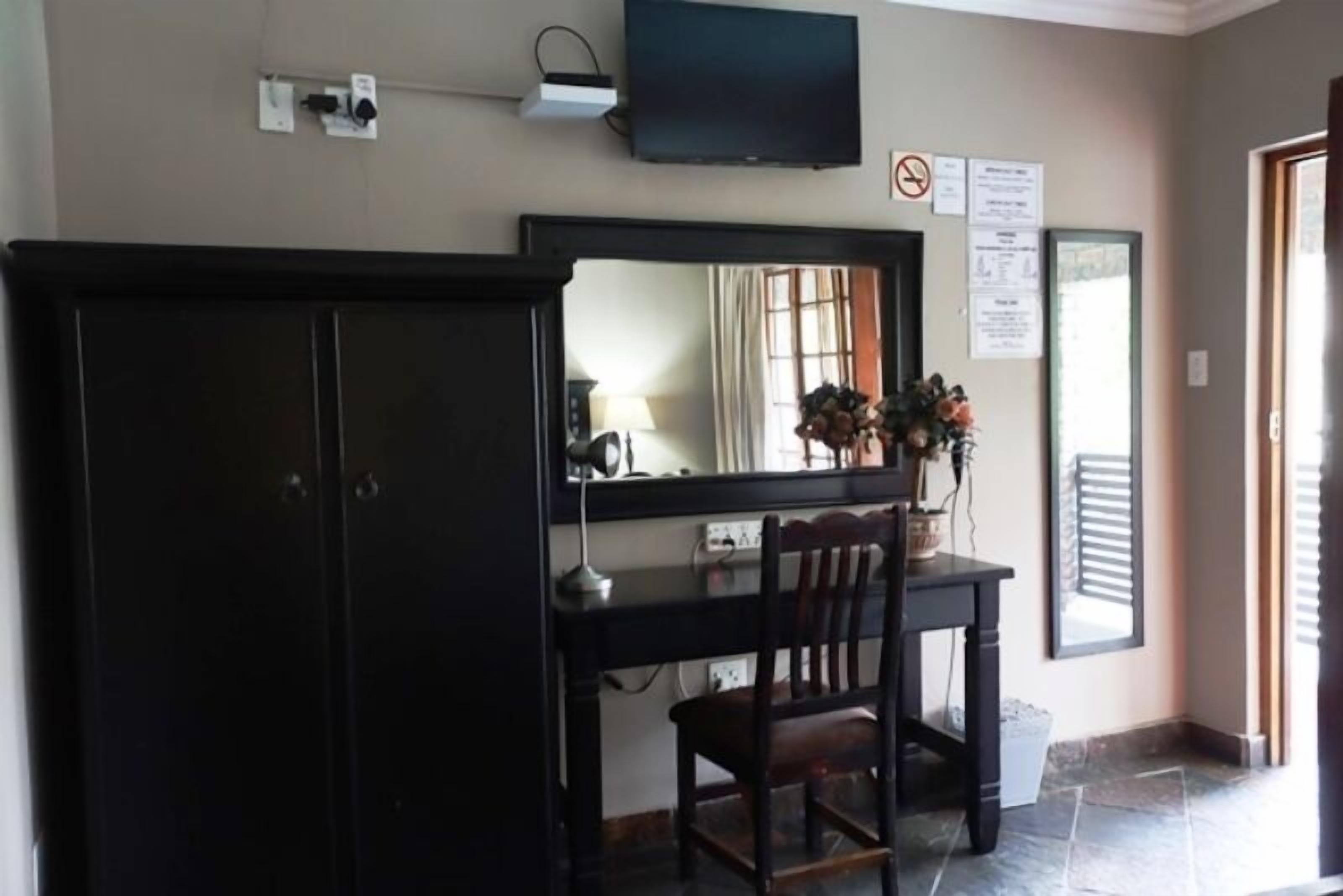 A room with a desk, chair, and a television mounted on the wall.