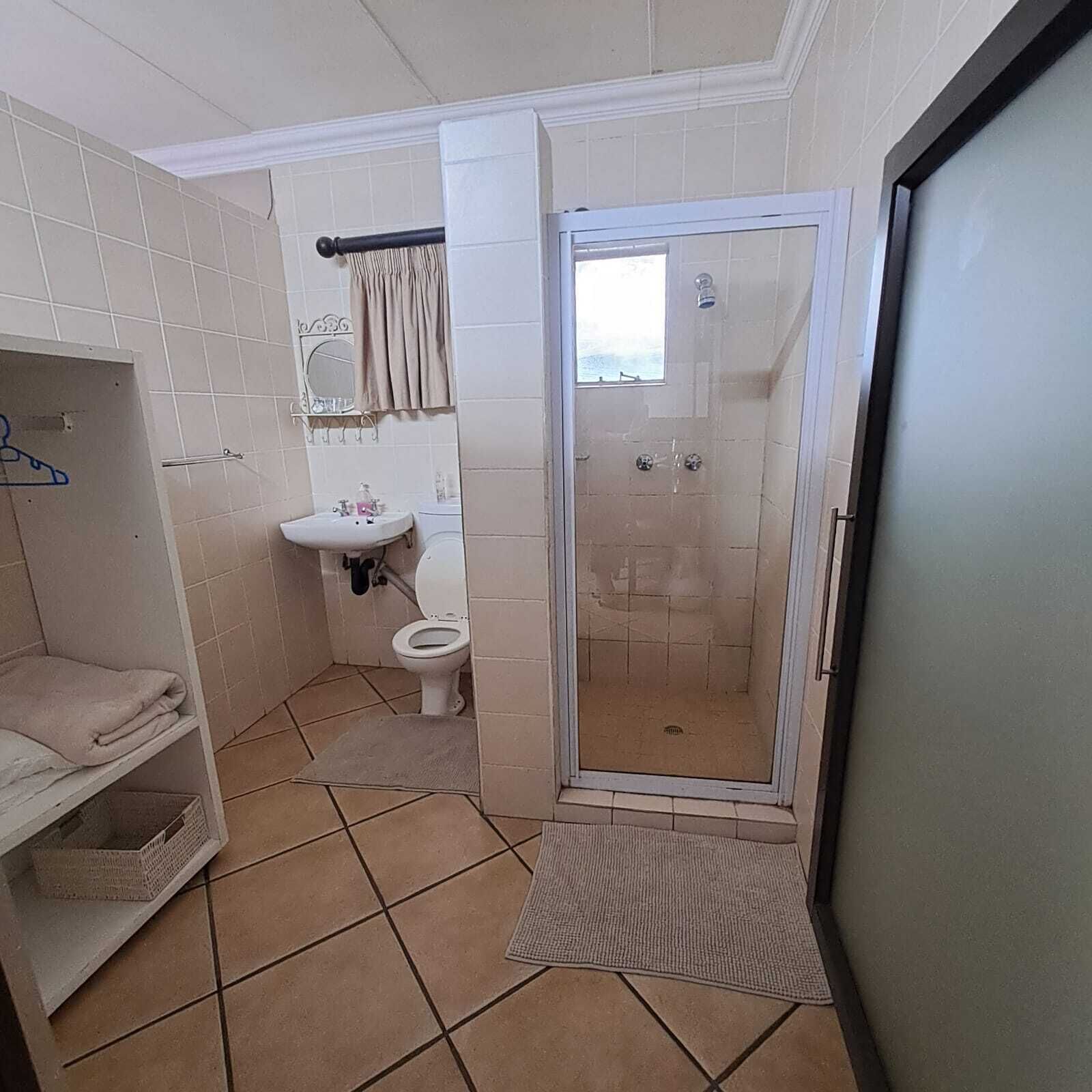 Une salle de bain avec des toilettes, un lavabo et une douche.