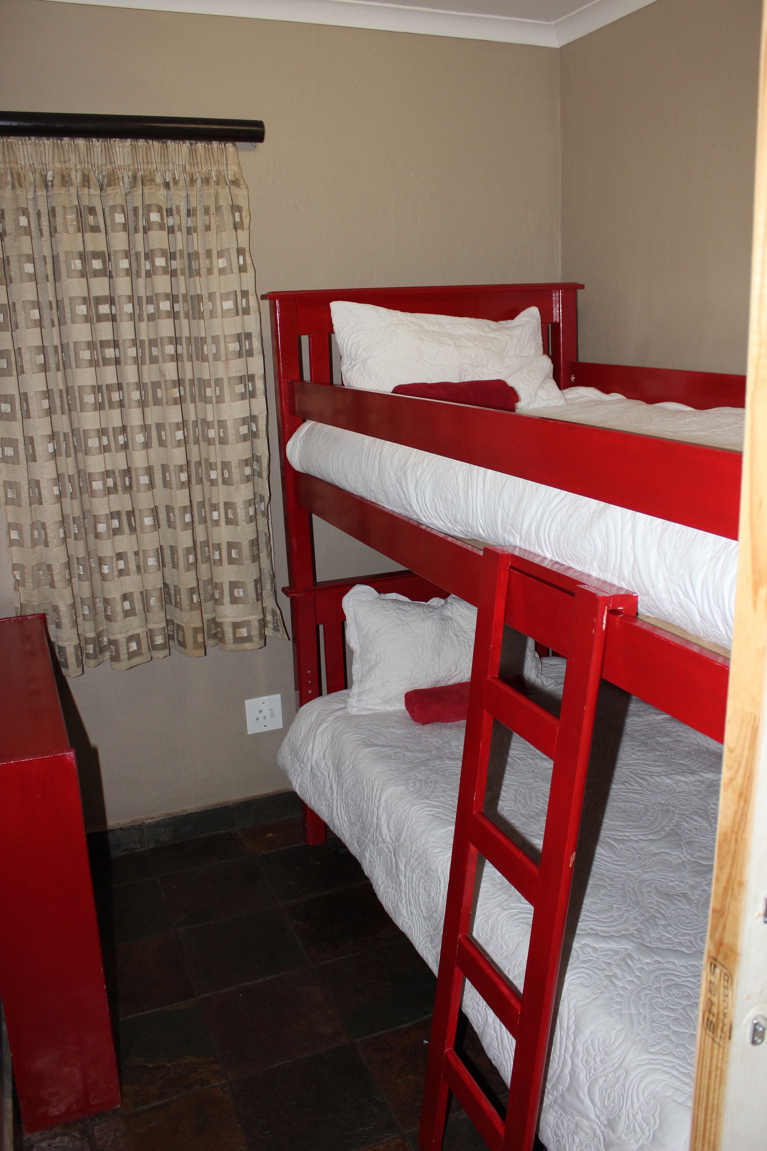 A bunk bed room with a curtain and a red desk.
