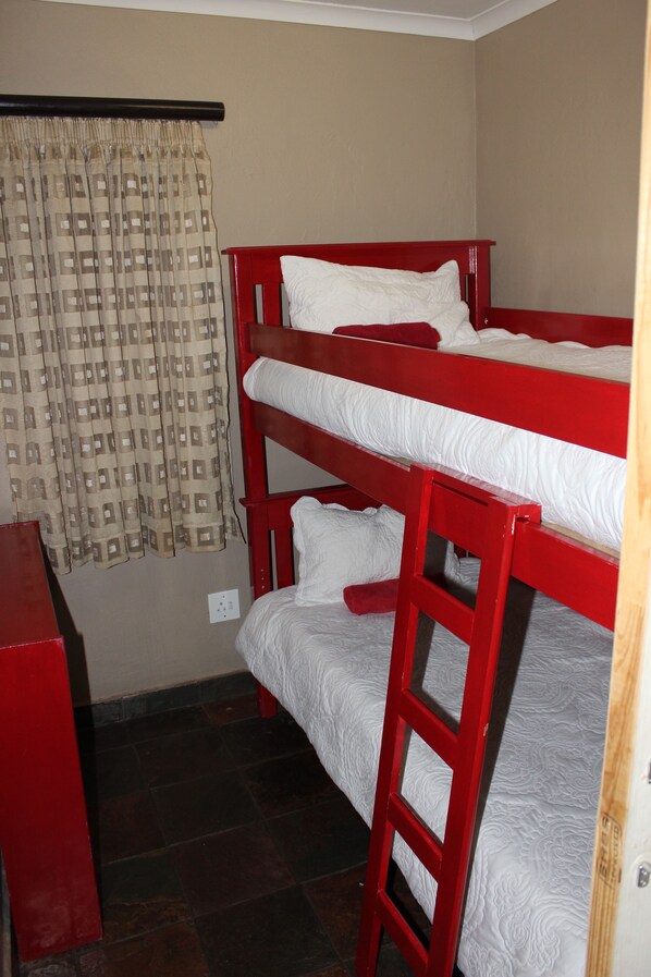 Habitación con literas, una cortina y un escritorio rojo.