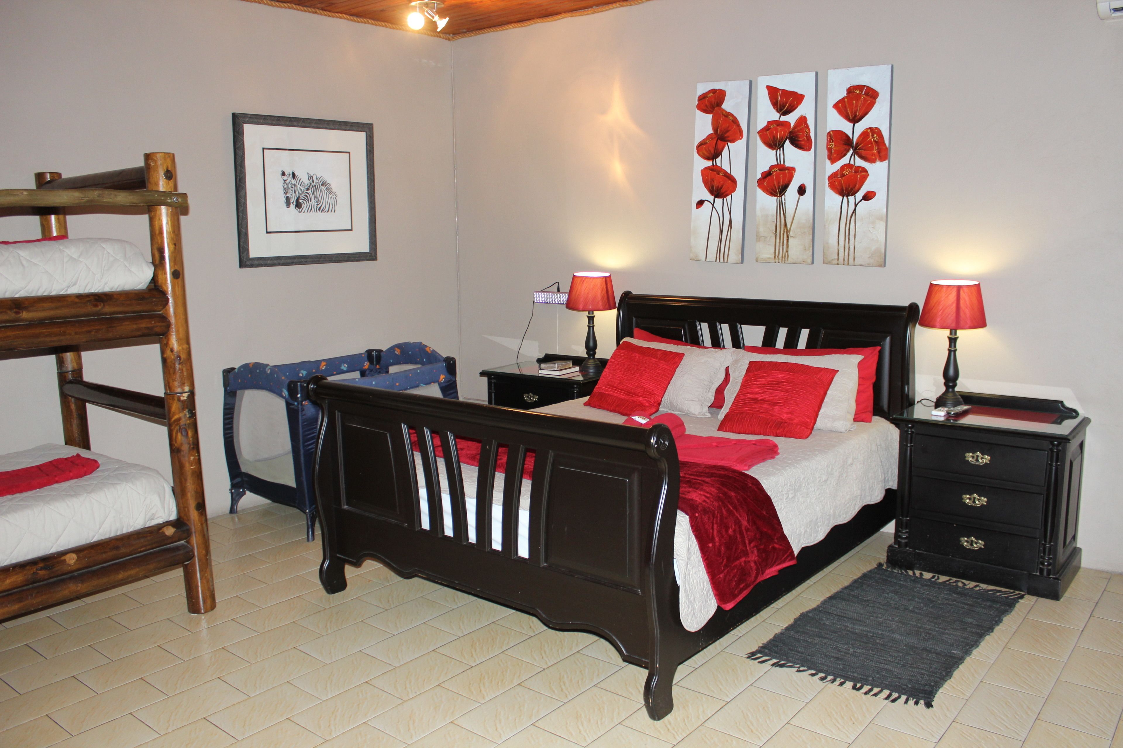 Une chambre à coucher avec un lit en bois, deux tables de chevet, une commode, une chaise bleue et un tableau représentant une zèbre, encadré, accroché au mur.