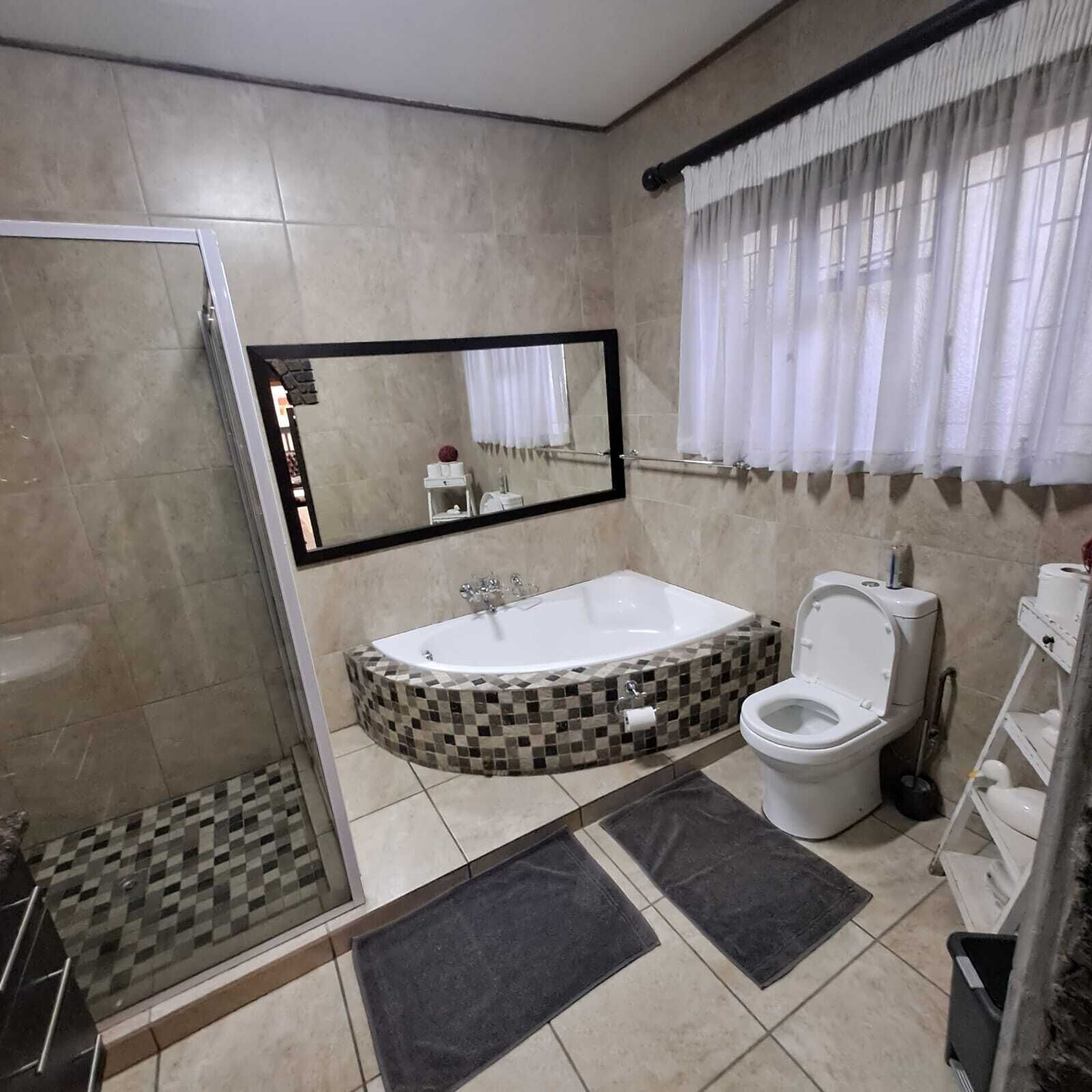 A modern bathroom with a glass-enclosed shower, a freestanding bathtub, and a toilet.