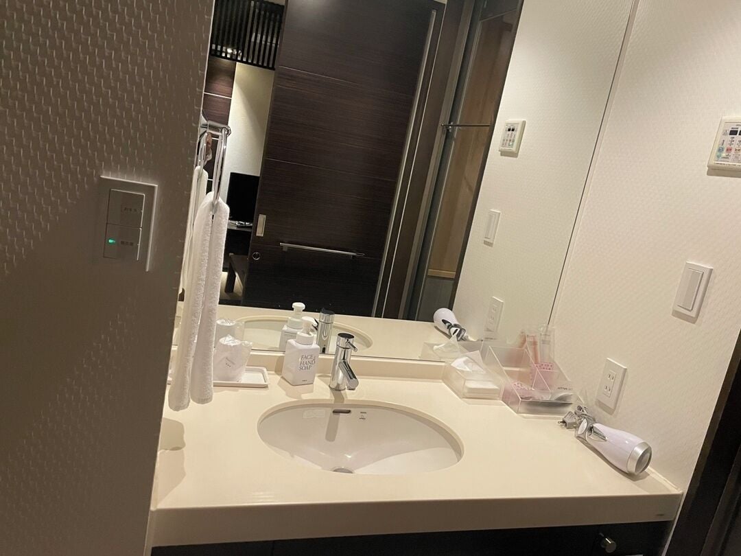 A hotel bathroom with a large mirror, a sink, and toiletries.