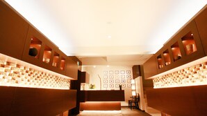 Un interior moderno con una escalera central, iluminación empotrada y una pared decorada con cuadros.