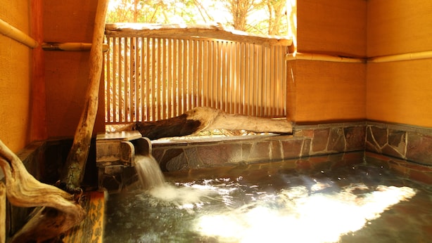 Un área de aguas termales con un banco de madera y un muro de piedra.