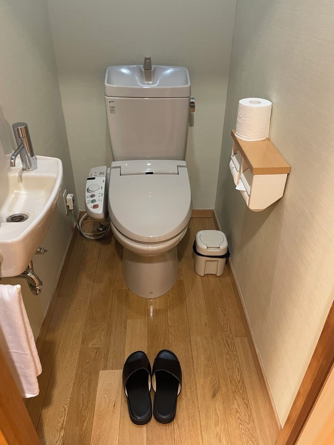 Une petite salle de bain comprenant des toilettes, un lavabo et une étagère avec du papier toilette.