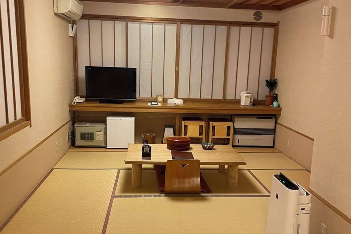 Una tradizionale stanza in stile giapponese con pavimento in tatami, televisione, un piccolo frigorifero e un forno a microonde.