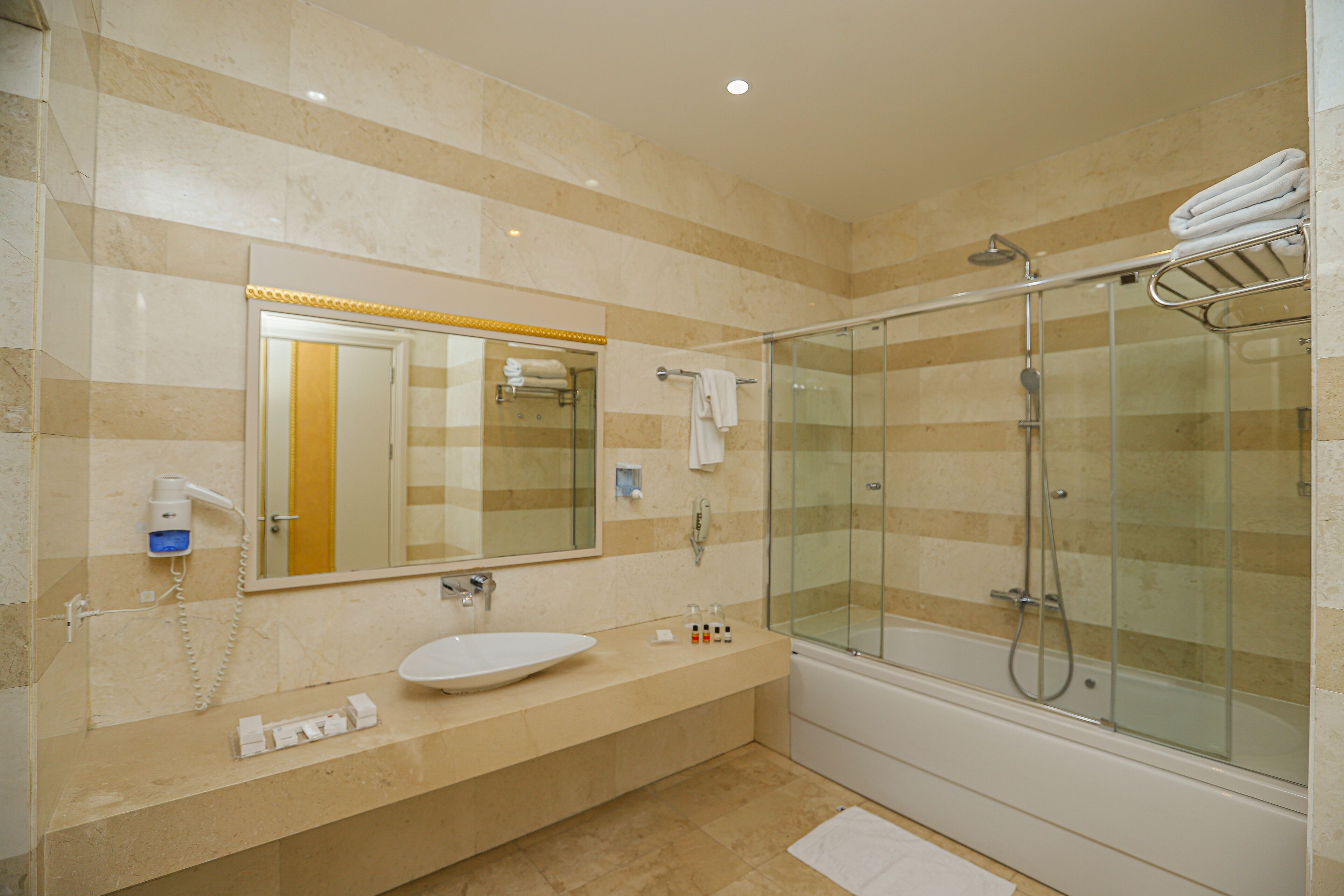 A modern bathroom with a glass-enclosed shower, a large mirror, and a vanity with a sink and towel rack.