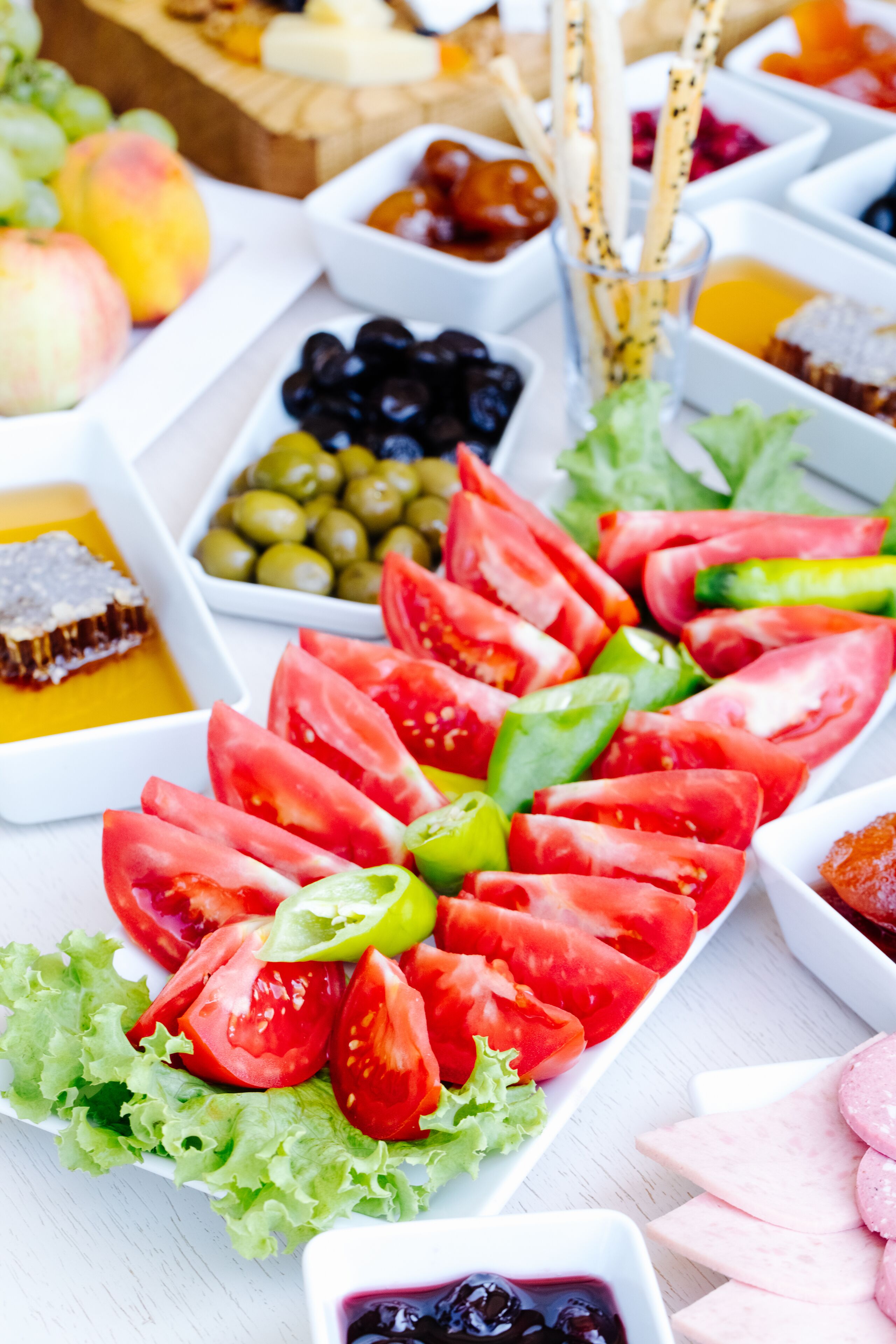 Une variété d’aliments, notamment des tomates en tranches, des olives et d’autres fruits et légumes, disposés sur un plateau blanc.
