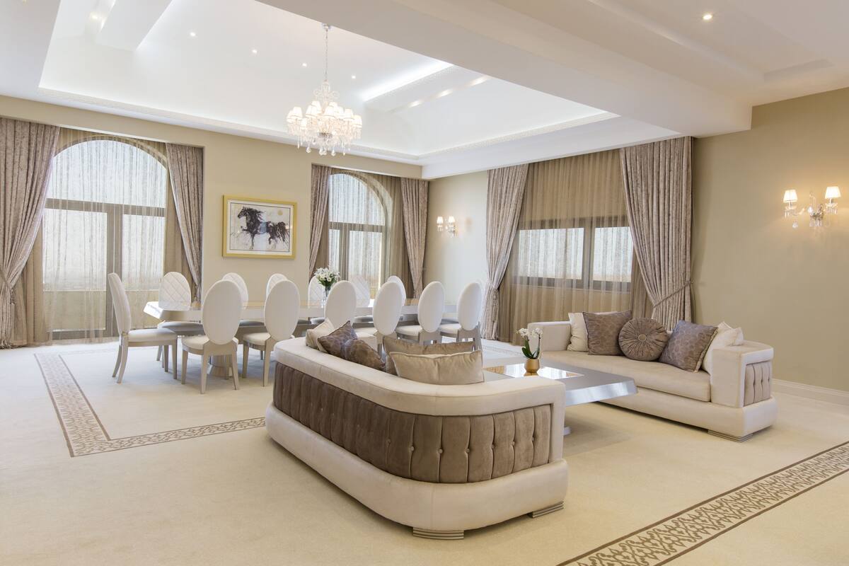 A spacious living room with a large dining table, a sofa, and a chandelier.