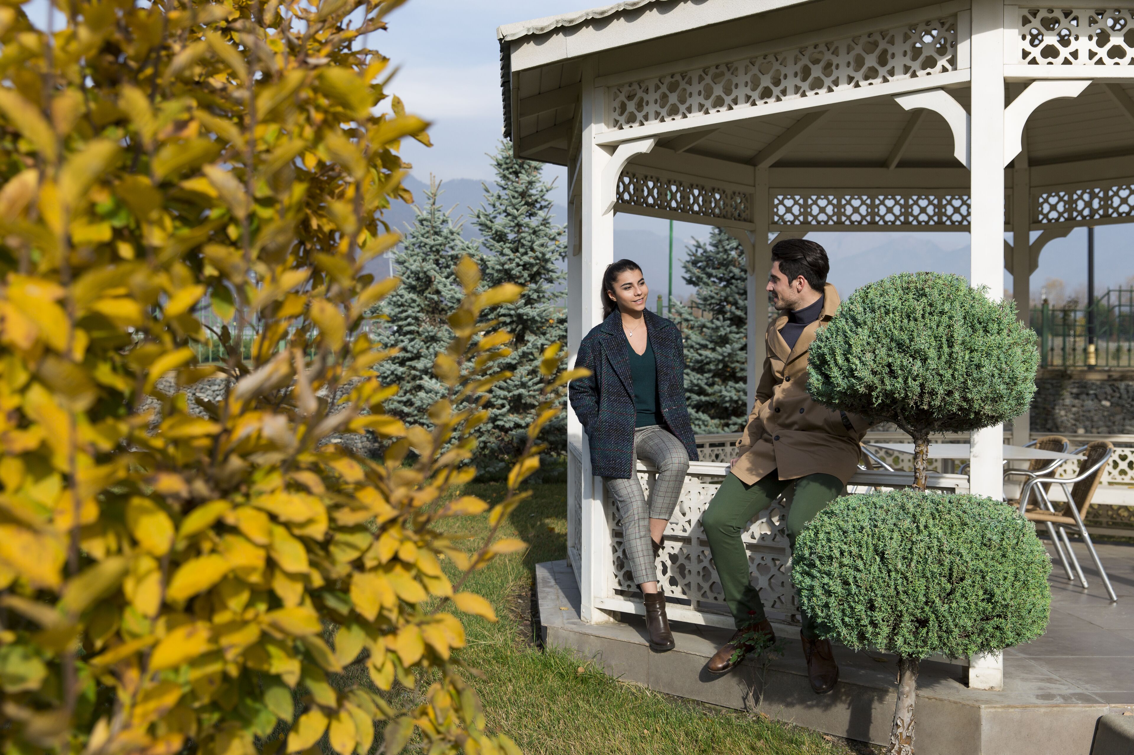 A gazebo with intricate lattice work, a small table, and chairs.