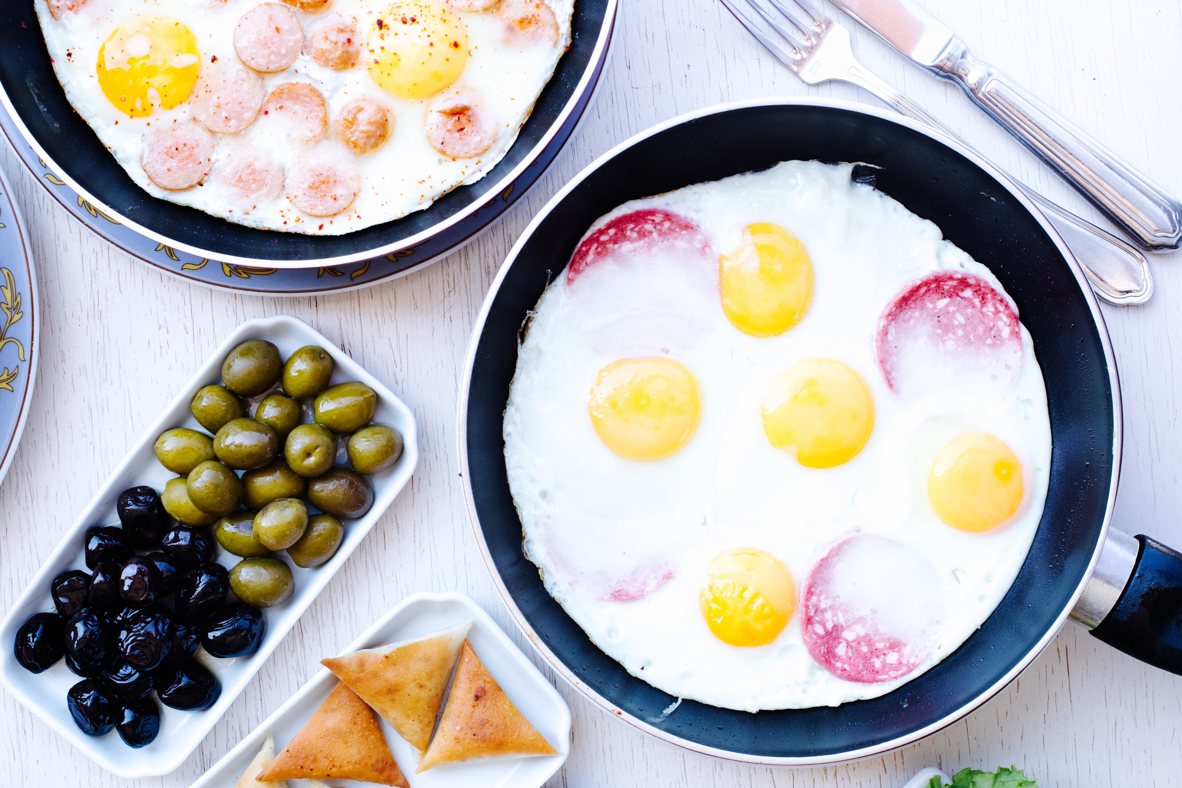 Un plato de desayuno con huevos, salchicha y aceitunas.