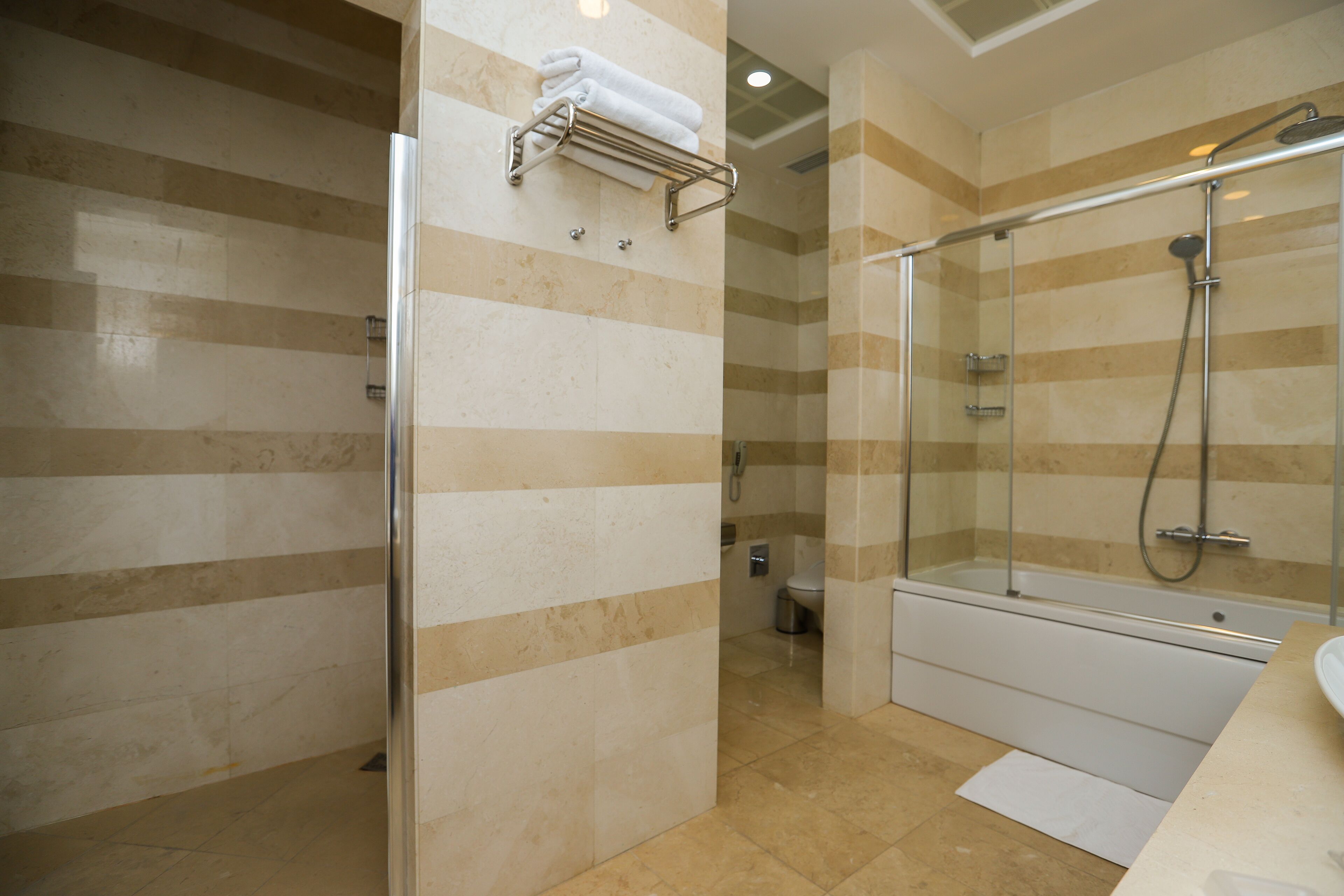 A modern bathroom with a glass-enclosed shower, a glass door, and a towel rack.