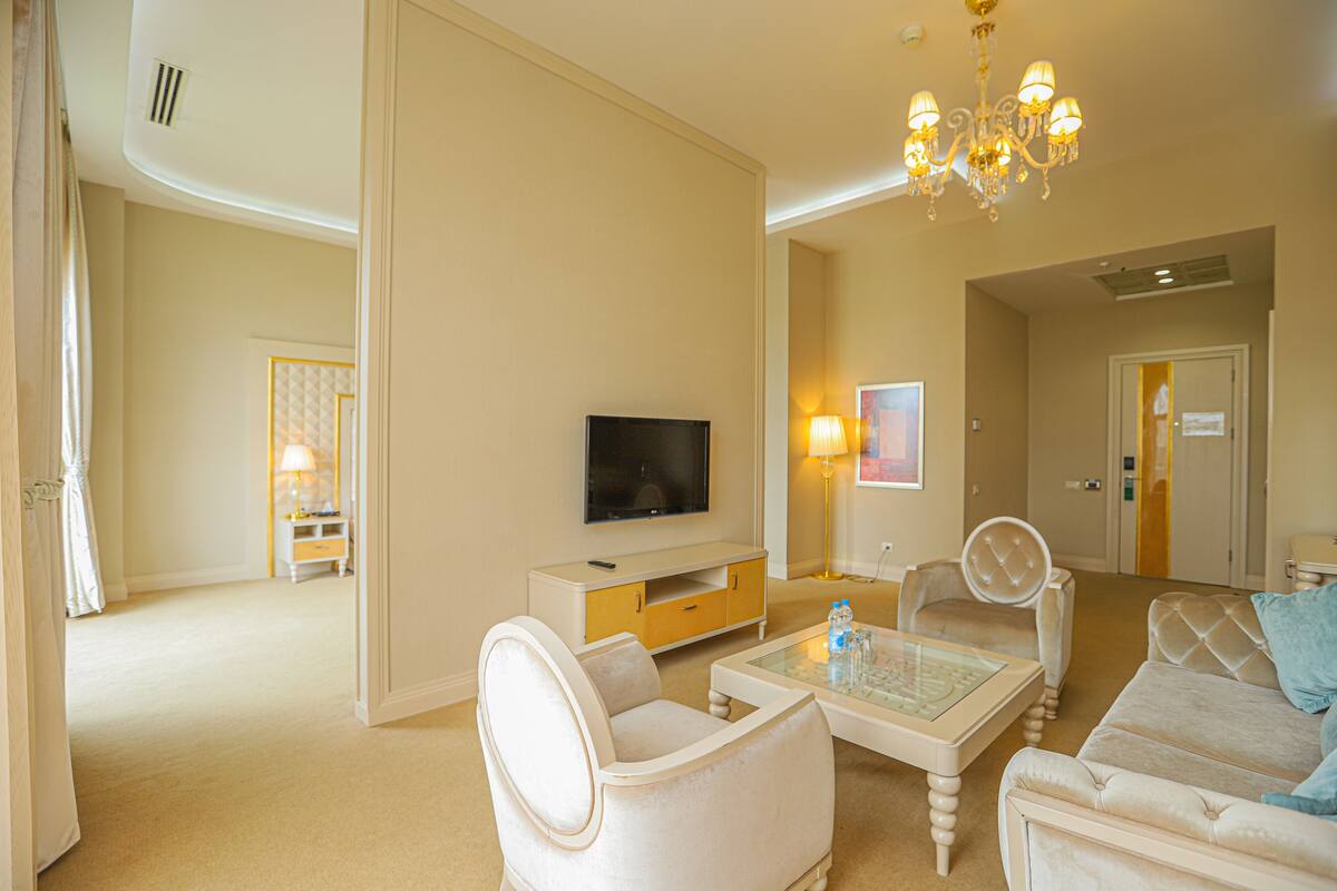 A spacious living room with a flat-screen TV, a glass coffee table, and a sofa.