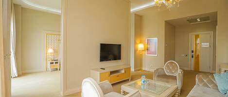 A spacious living room with a flat-screen TV, a glass coffee table, and a sofa.