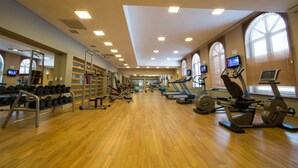 Un gimnasio con equipo de ejercicio, espejos y ventanas amplias.