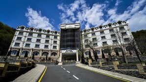 Un hotel con entrada central, varios pisos y fachada moderna de vidrio.