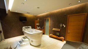 Un baño moderno con una bañera grande, una puerta de madera y un banco con una bandeja de fruta.