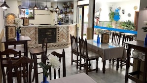 A restaurant with a bar area, wooden tables, and chairs. - Apartamentos La Fuente (Córdoba)