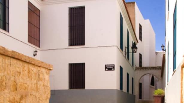 A set of stone steps leading up to a white building with a tiled roof and a small garden area at the top. - Apartamentos La Fuente (Córdoba)