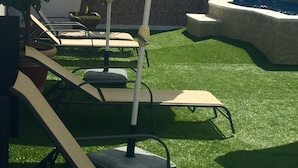 A poolside area with lounge chairs, a water feature, and a stone wall. - Apartamentos La Fuente (Córdoba)
