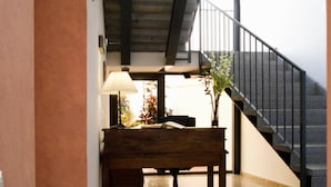 A wooden desk with a lamp, a bench, and a staircase in the background. - Apartamentos La Fuente (Córdoba)
