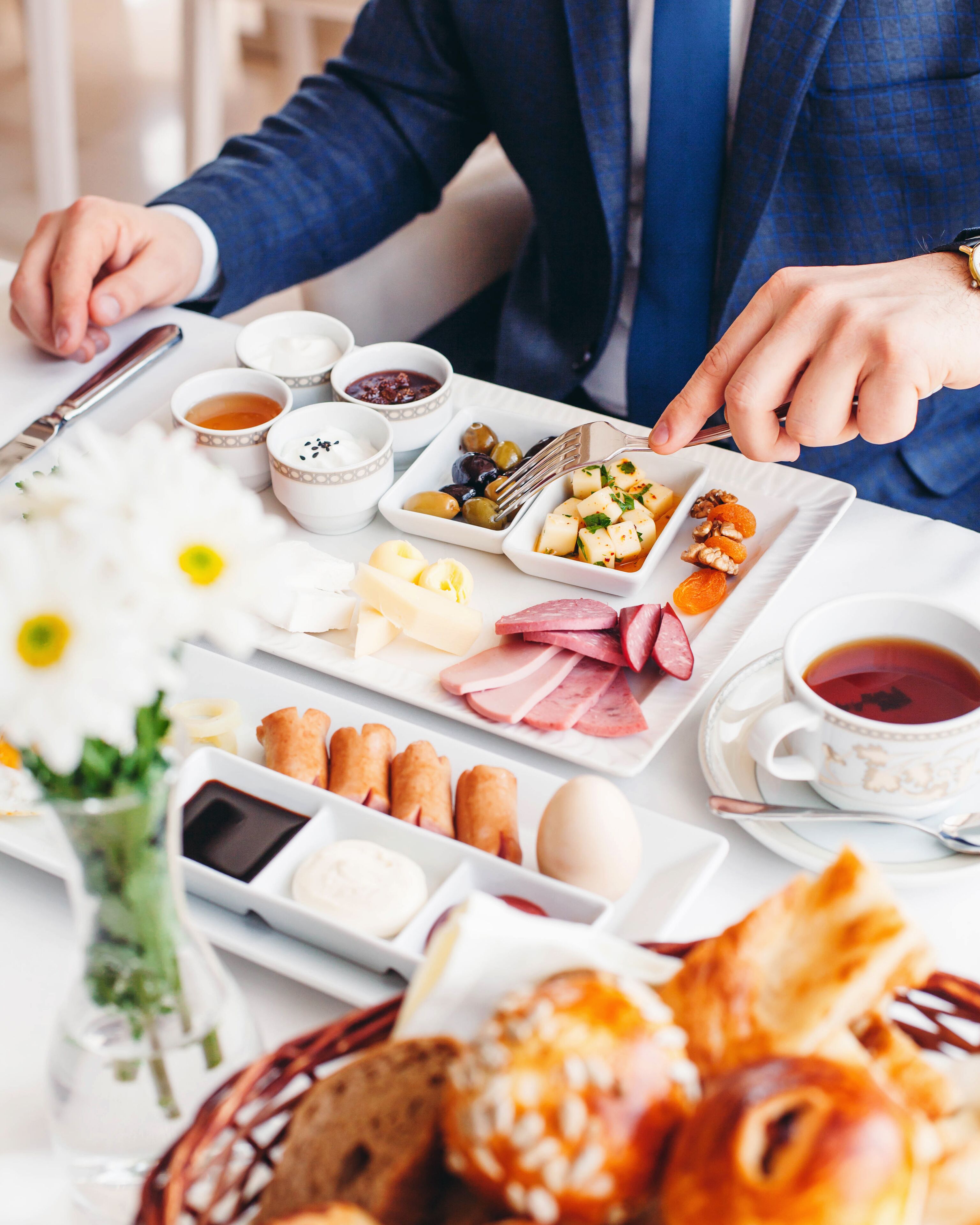 A breakfast setting with various food items, including eggs, cheese, and pastries, on a white table.