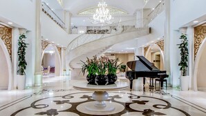 A grand lobby with a large chandelier, a grand piano, and ornate floor designs. - Qafqaz Riverside Resort Hotel (Gabala)