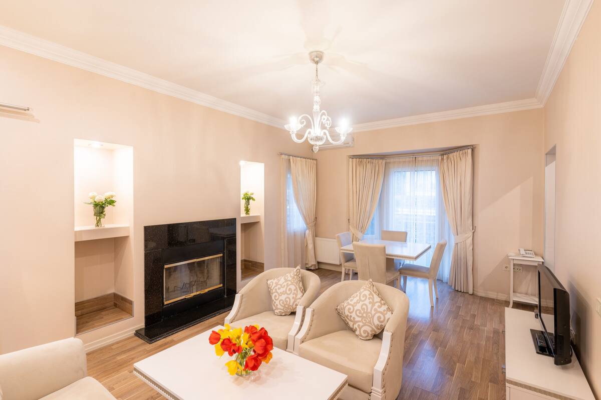 A spacious living room with a fireplace, comfortable seating, a dining area, and a television.