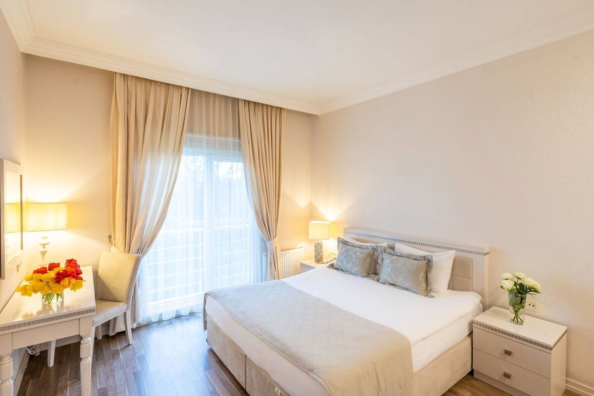 A hotel room with a large bed, bedside tables, a desk, and a chair.
