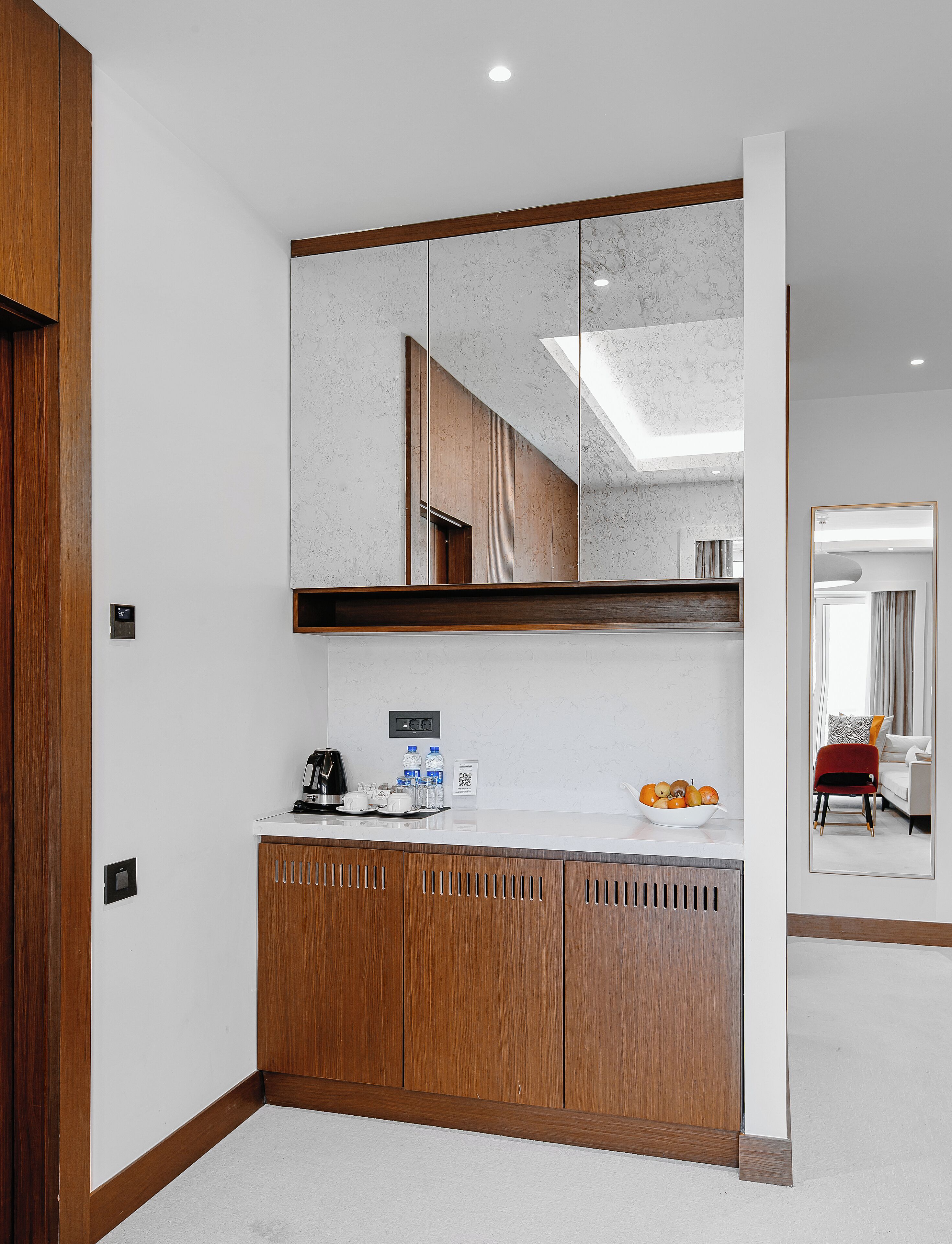 Une salle de bain moderne avec un grand miroir, des meubles en bois et un plan de toilette où sont posés les articles de toilette.