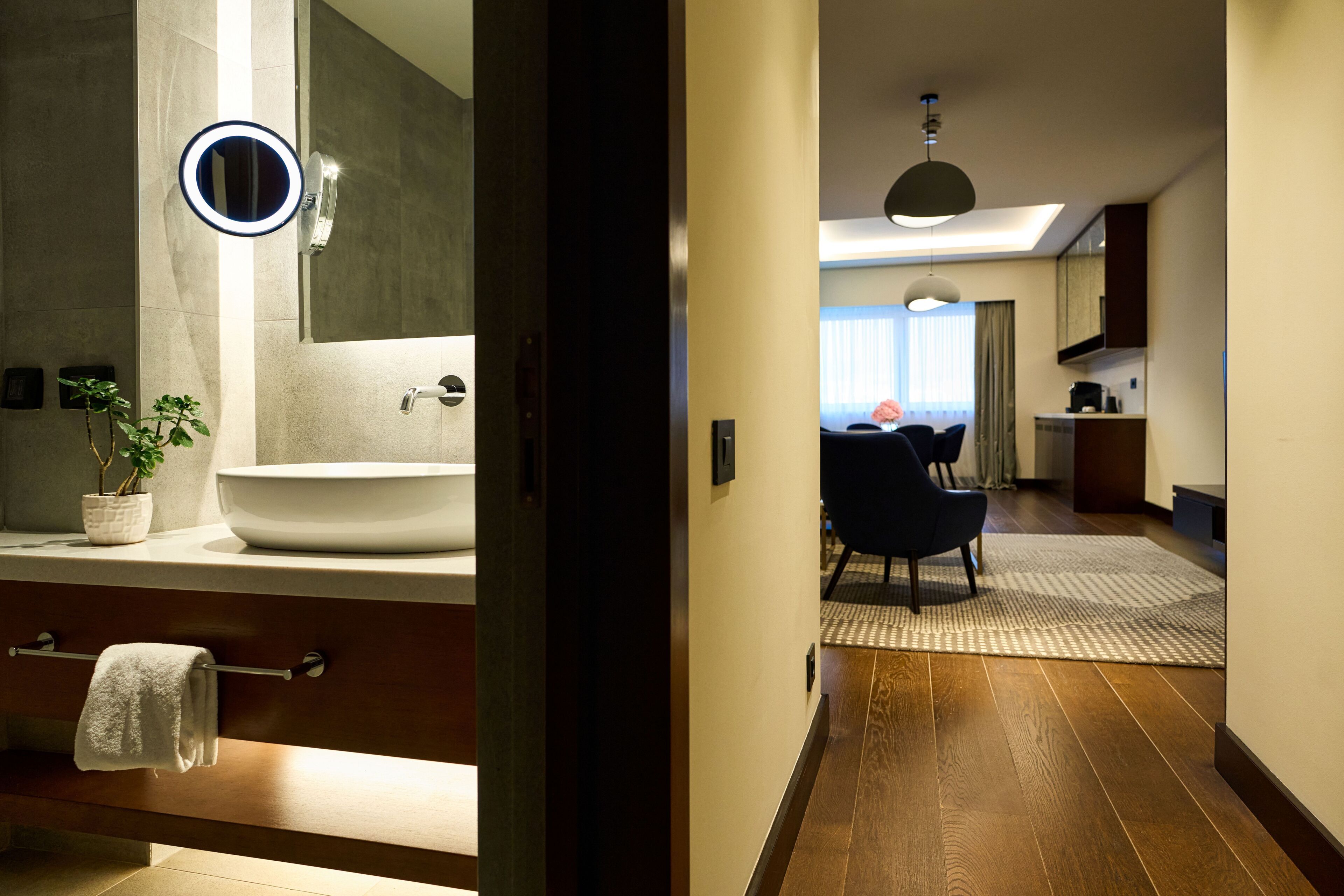 Un baño moderno con un lavamanos grande, espejo y perchero.